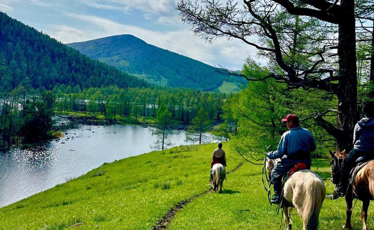 Riders following a trail above a river valley in the Khangai Mountains of Mongolia